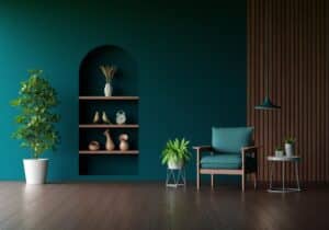 Modern living room with teal accent wall, wooden shelving, indoor plants, armchair, and pendant light for stylish interior design