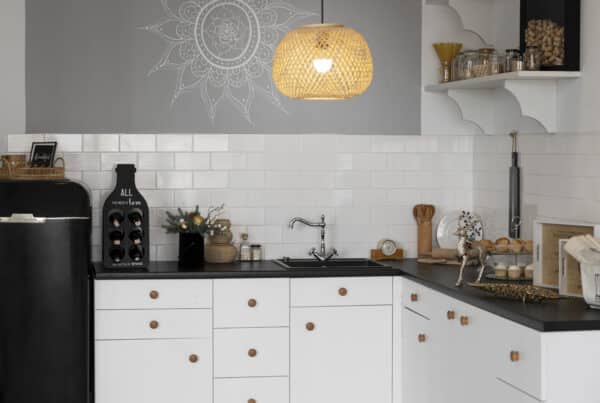 Modern custom kitchen with white cabinets, black countertop, wooden knobs, open shelving, built-in sink, and pendant light, showcasing efficient storage and minimalist design.
