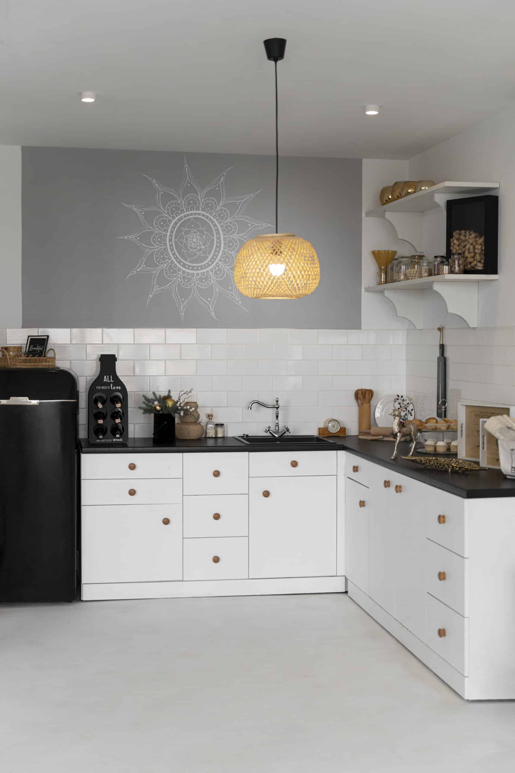 Modern custom kitchen with white cabinets, black countertop, wooden knobs, open shelving, built-in sink, and pendant light, showcasing efficient storage and minimalist design.